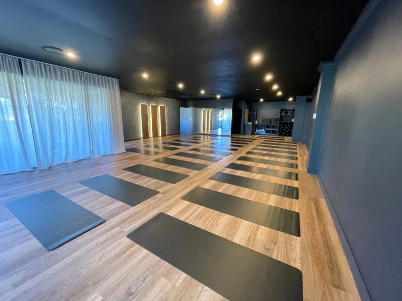 Inside the Flolo Robina studio, warm timber floors, dark walls and mats laid out